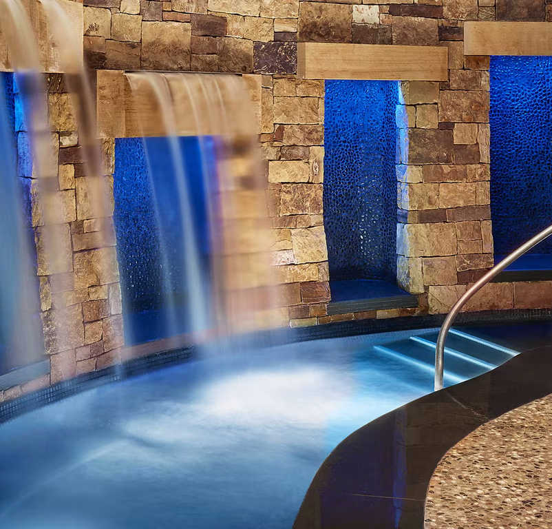 The RAKxa Wellness Spa in Aspen with cascading waterfalls and stone walls, creating a serene atmosphere.