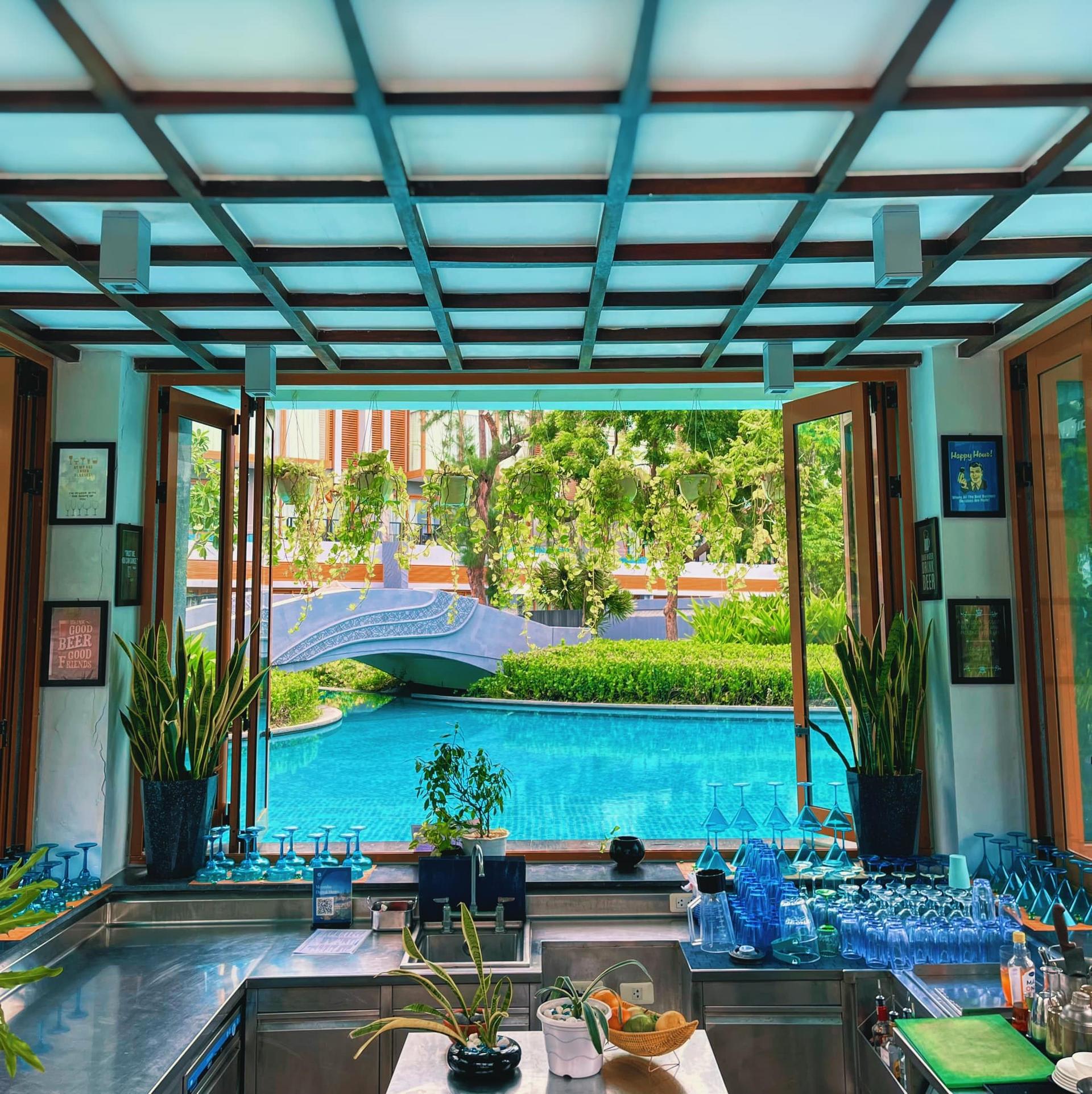 View of the pool bar with lush greenery and a bridge at Banyan Tree Lang Co, Vietnam.