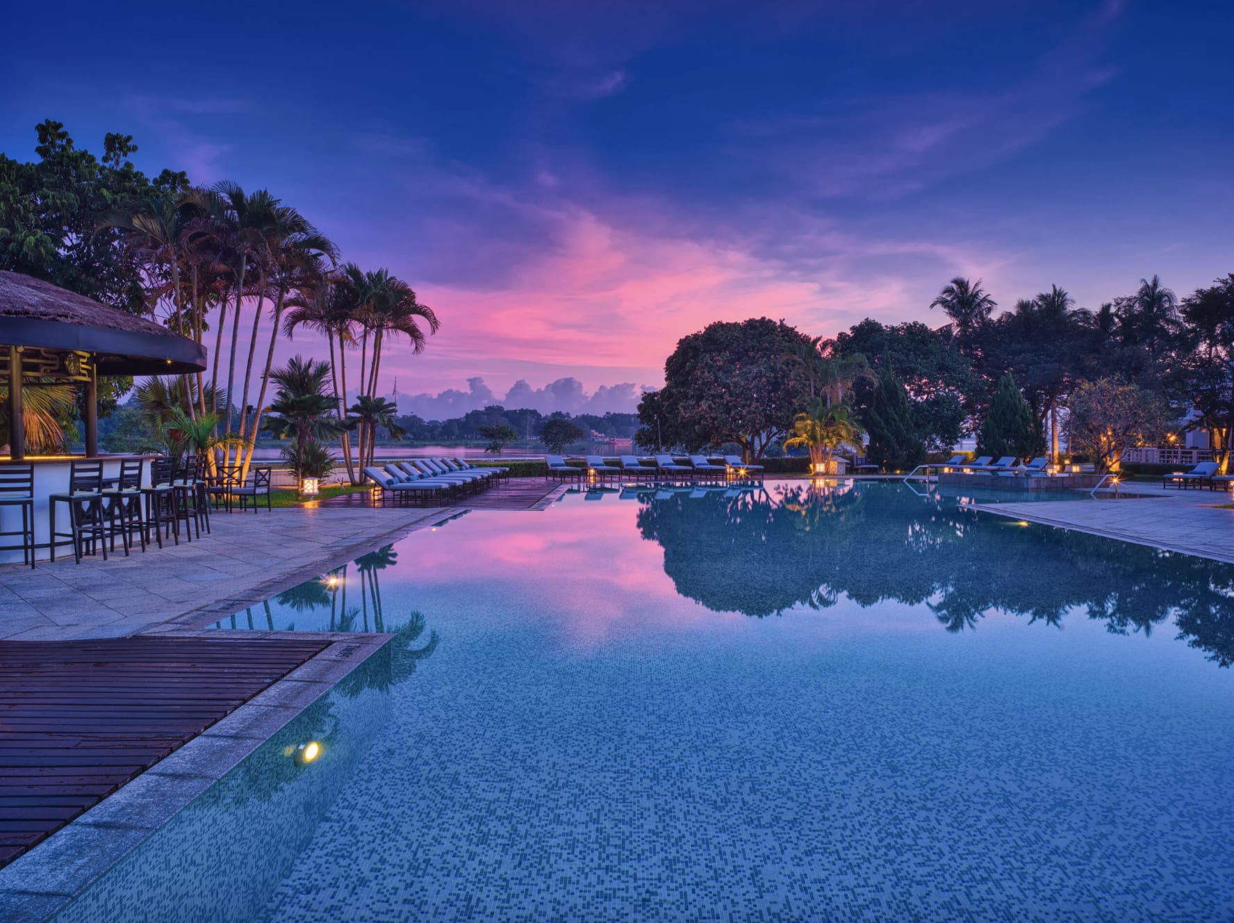 Twilight view of a serene poolside area with palm trees at Banyan Tree Lang Co, Vietnam.