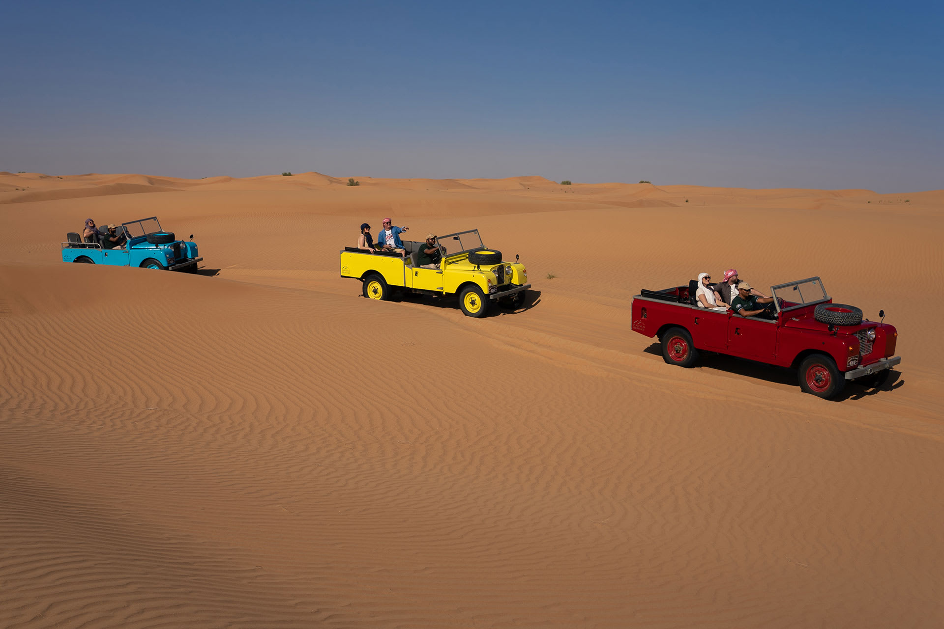 Tour safari jeeps driving through the sand dunes of Dubai.