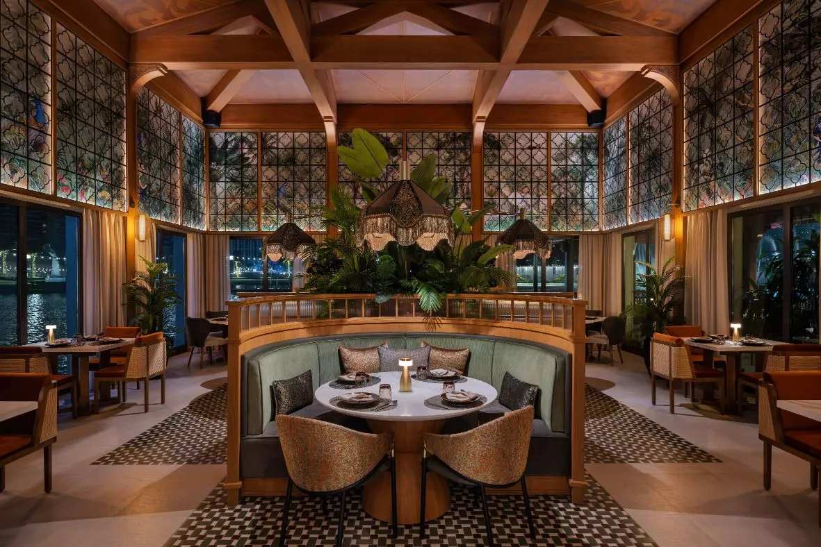 Elegant restaurant interior with a circular booth, lush greenery, and stained glass windows, creating a cozy ambiance.