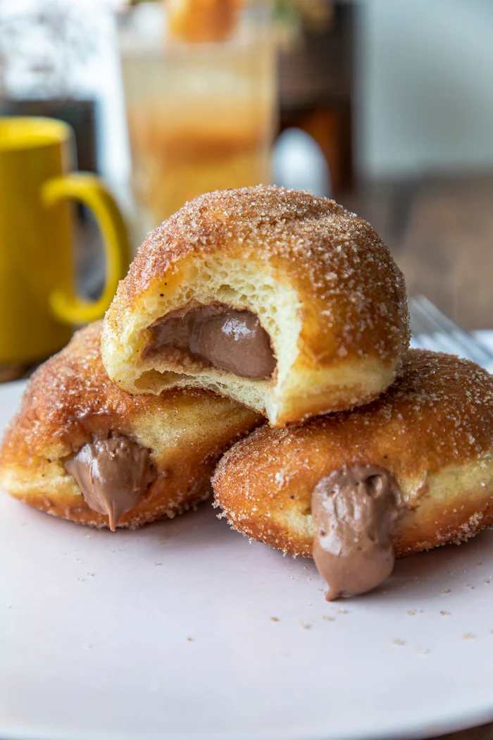 Close-up of three cinnamon sugar donuts at Millers filled with creamy chocolate filling, one donut with a bite taken out.