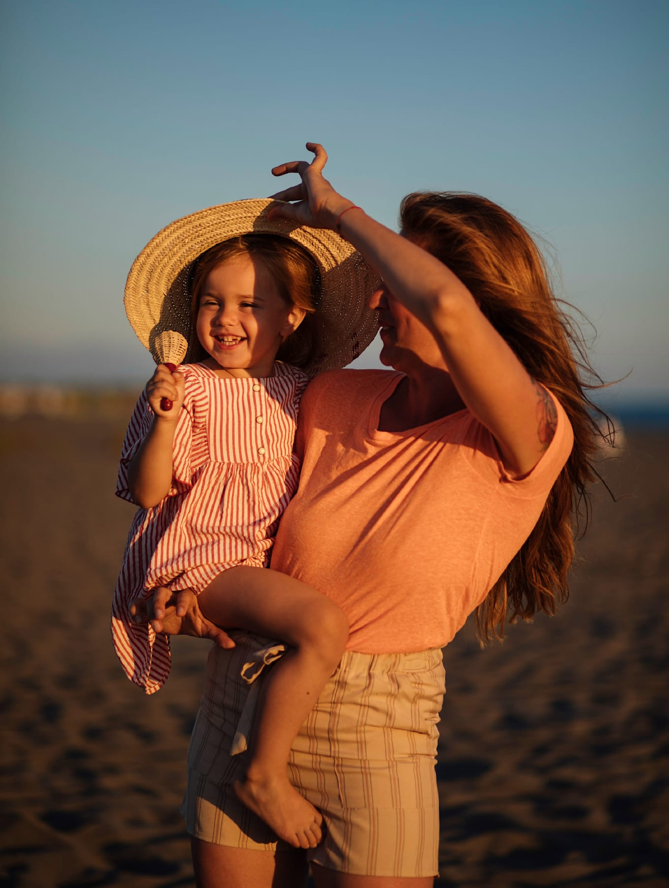 Mother and child enjoying a playful moment on the beach at sunset.