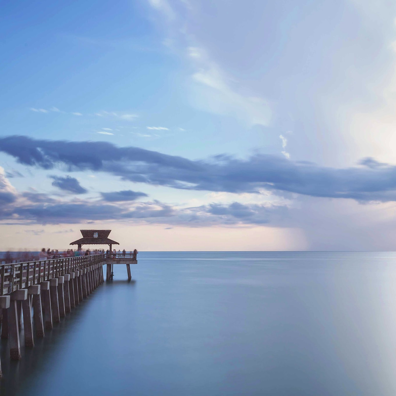 A pier extending into the calm waters at sunset near Exclusive Resorts properties in Naples, Florida.